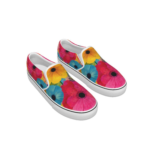 A pair of slip-on canvas sneakers with a vibrant floral print featuring pink, yellow, and blue flowers with black centers, set against a plain white background.